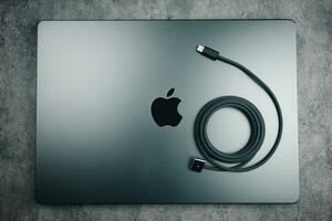 Bangkok, Thailand - December 5, 2023 Space Black M3 Max MacBook Pro with black braided USB C port for fast charge placed on top photo
