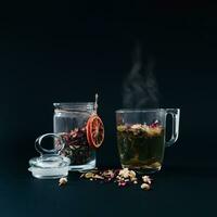Creative layout made with cup of herbal tea with various herbs on dark background. Minimal tea concept. Trendy hot drink idea. Herbal tea aesthetic. photo