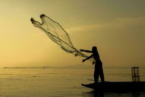 silueta pescador con puesta de sol cielo en el lago. foto