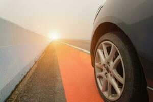 cerca arriba de rueda coche estacionamiento en el asfalto la carretera con luz de sol. foto