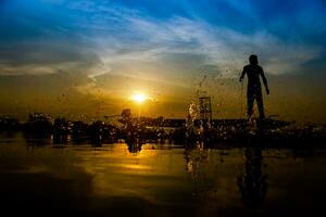 silhouette fisherman with sunset sky on the lake. photo