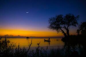 silueta de pescador y hijo con crepúsculo cielo. foto