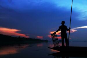 silueta pescador con puesta de sol cielo en el lago. foto