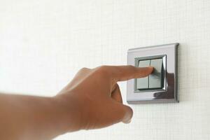 A finger turning on lighting switch . photo