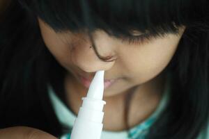 cerca arriba de enfermo niño utilizando nasal medicina rociar foto