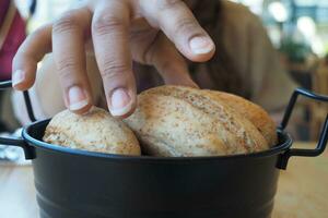 women hand pick baked bun on table photo