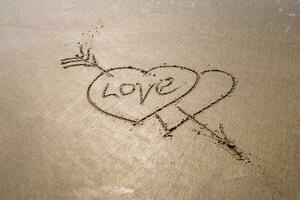 drawing in sand in form of two hearts and inscription love photo