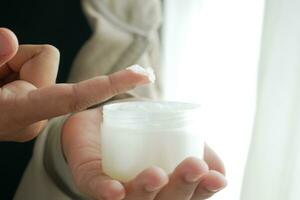 woman using petroleum jelly onto skin at home close up. photo