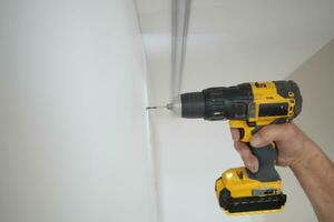 using electric drilling on white wooden board photo