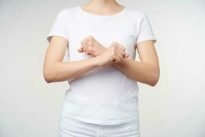 Horizontal shot of young fair-skinned female keeping hands crossed while expressing her thoughts on sign language, meaning word rest while standing over white background photo