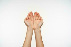 Studio shot of attractive fair-skinned hands of young female forming together, going to pick up water in folded palms. Body language and gesturing photo