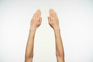 Close-up of beautiful woman's hand with manicure keeping fingers together while posing against white background, hand symbol viewed from back photo