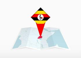 Uganda es representado en un doblada papel mapa y clavado ubicación marcador con bandera de Uganda. vector