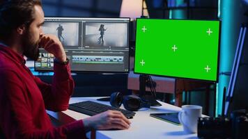 Video editor trimming segments of drone shot footage, using green screen PC monitor to work. Videographer splicing film pieces, editing them using professional software on mockup computer display