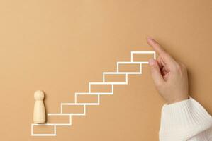 Wooden man and painted steps up on a brown background. photo