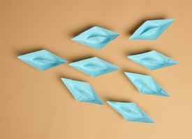 Group of paper boats on a brown background.Concept of a strong leader in a team, manipulation of the masses photo