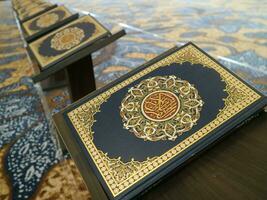 Close up look of holy Quran on tiny table with other quran books on the background. photo