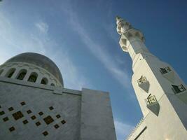 Solo, Central Java Indonesia - November 26, 2023 Low key angle shot of minaret and dome of Zayed mosque with blue sky on background. photo