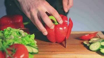 Koch im schwarz Uniform ist Schneiden rot Paprika und vorbereiten Gemüse Zutaten zum Kochen. Mann im ein Küche ist Schneiden rot Pfeffer zum Vegetarier Gericht. gesund Essen Konzept video