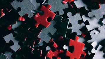 Background of Colored Puzzle Pieces that Slowly Rotating Counterclockwise Top View, CloseUp. Texture of Incomplete Red and Grey Jigsaw Puzzle with Low Key Light Left Rotation video