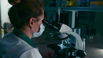 trabajo en el laboratorio con el luces apagado. examen de muestras de químico reactivos con un microscopio. video