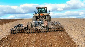 Rear view of tractor and plow plowing and preparing soil for sowing. A tractor prepares soil for crops on a sunny day video