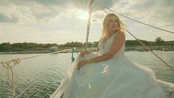 brud på en Yacht på solnedgång. de brudens blick i de distans, de solens strålar video