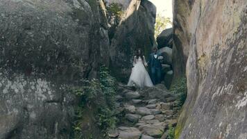 jung Paar im das Berge. Jungvermählten Gehen zwischen das Felsen. das Bräutigam hält das Hand von das Braut. video