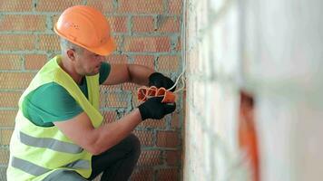 un trabajador instala un salida. reparar trabajo en el habitación. construcción video