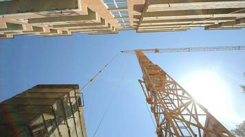 construction crane bottom view. Construction of a house. The sun's rays shine through a construction crane. video