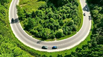 antenne visie van de snelweg voorbijgaan door de bergen en Woud Oppervlakte. auto's in beweging langs de spoor. reizen in de bergen in de zomer door auto. video