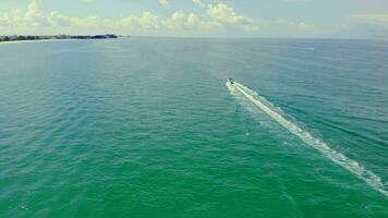 parte superior ver de un lancha rápida dejando el Florida cerca el línea costera en un nublado día. transporte de un motor barco en el mar. video