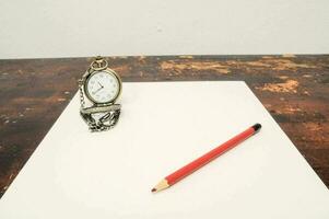 a pocket watch and pencil on a table photo