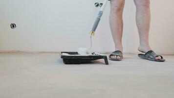 Painting the walls in the room. A male craftsman applies white paint closeup to a paint roller. video