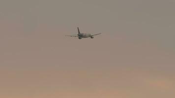 PHUKET, THAILAND FEBRUARY 22, 2023 - Airbus A320 232, HS TXB of Thai Smile flying at sunset or dawn, long shot, rear view. Airliner gaining altitude after takeoff. Travel concept video