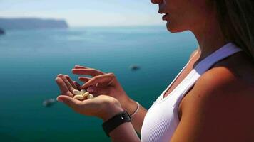 mujer comiendo lechoso almendra nueces. un joven caucásico mujer comiendo Fresco almendra después Mañana aptitud yoga cerca mar. solamente manos son visiblemente. sano vegano alimento. lento movimiento video