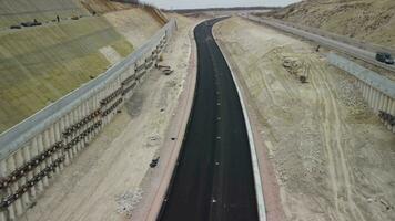 Workers reinforce the slope over the new road. Road construction in progress on slope nature canyon. Infrastructure development and logistics. Aerial drone shot video