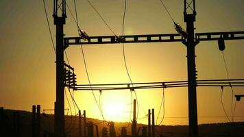 High voltage electric transformer station and distribution network at sunset. Power transmission lines on supports with ceramic insulators and transformers at large electrical distribution substation video