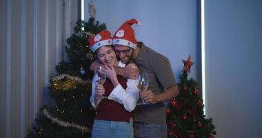 Portrait of  Young man are embracing their girlfriends, holding a glass of wine and enjoying standing beside the Christmas tree in the room,Lovers have moment romantic and happy together photo