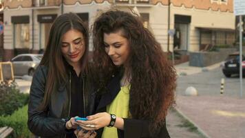 Female friends watch photos on smartphone video