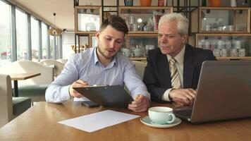 Business partners discuss some project at the cafe video