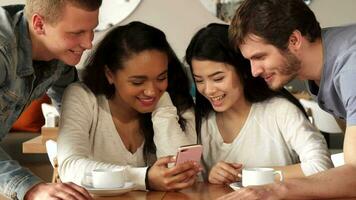 Four friends watch something on smartphone at the cafe video