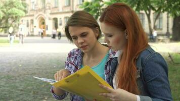 Female students look at some journal on campus video