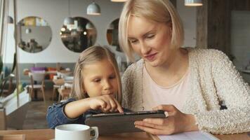 Mother and daughter use tablet at the cafe video