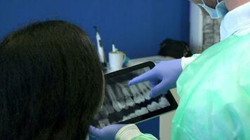 Dentist shows the patient xray on tablet video