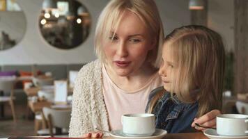 Little girl whispers in her mother's ear at the cafe video