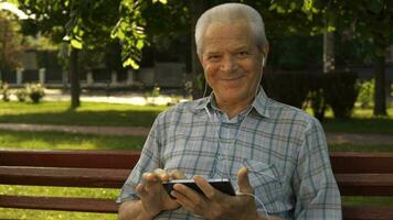 Senior man uses tablet on the bench video