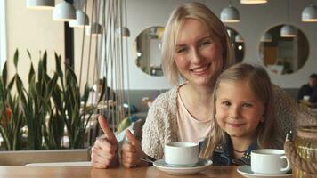 Mother and daughter shows their thumbs up at the cafe video