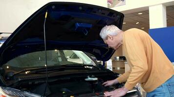 Senior man looks at engine compartment video