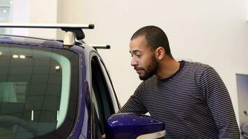 Man stands near the purple crossover at the showroom video